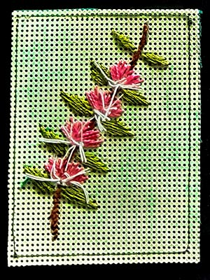 Artist trading card featuring embroidered flower spray on a green mesh background