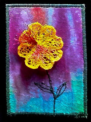 Artist trading card with a yellow flower on a multicoloured background in blues, greens and purples