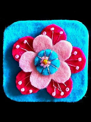 Multilayered fabric flower in pinks and blues on a blue background