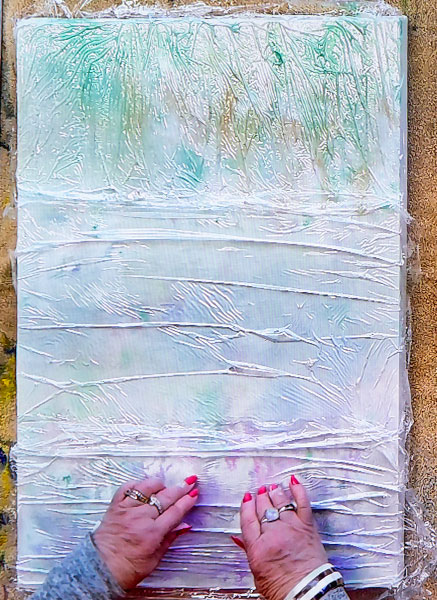 Applying plastic cling wrap to wet canvas.